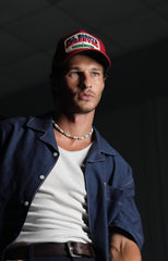 Man wearing All Rights Reserved Red Trucker Hat and casual outfit against a dark background