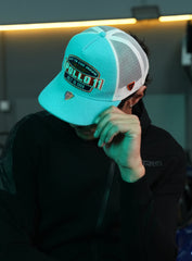 Person wearing Apollo Blue Trucker Hat, sitting indoors.