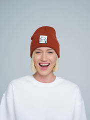 Person wearing a brown beanie with a logo on a plain background