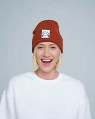 Person wearing a brown beanie with a logo on a plain background