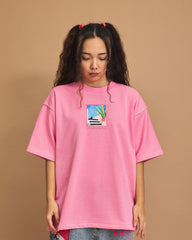 Person wearing a pink t-shirt with a graphic design on a brown background