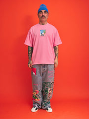 Person wearing a pink t-shirt and gray pants with colorful designs against an orange background