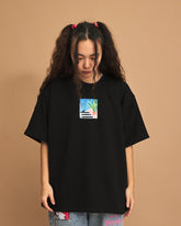 Person wearing a black t-shirt with a small graphic on a brown background
