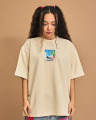 Person wearing a beige t-shirt with a colorful graphic on a brown background