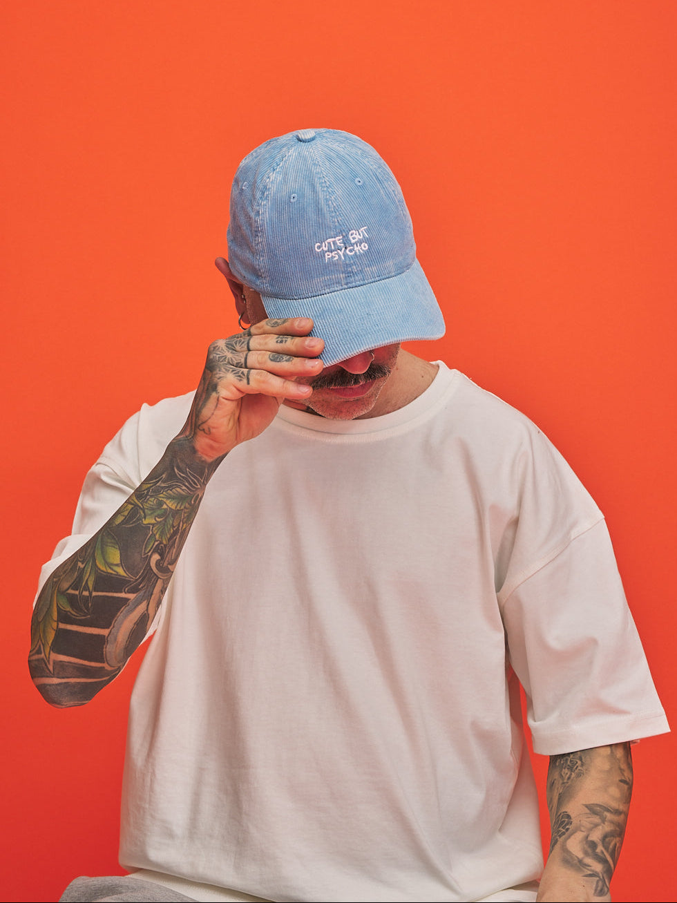 Person wearing a blue cap and white t-shirt against an orange background