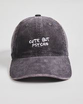 Gray corduroy cap with 'Cute But Psycho' text on a light gray background