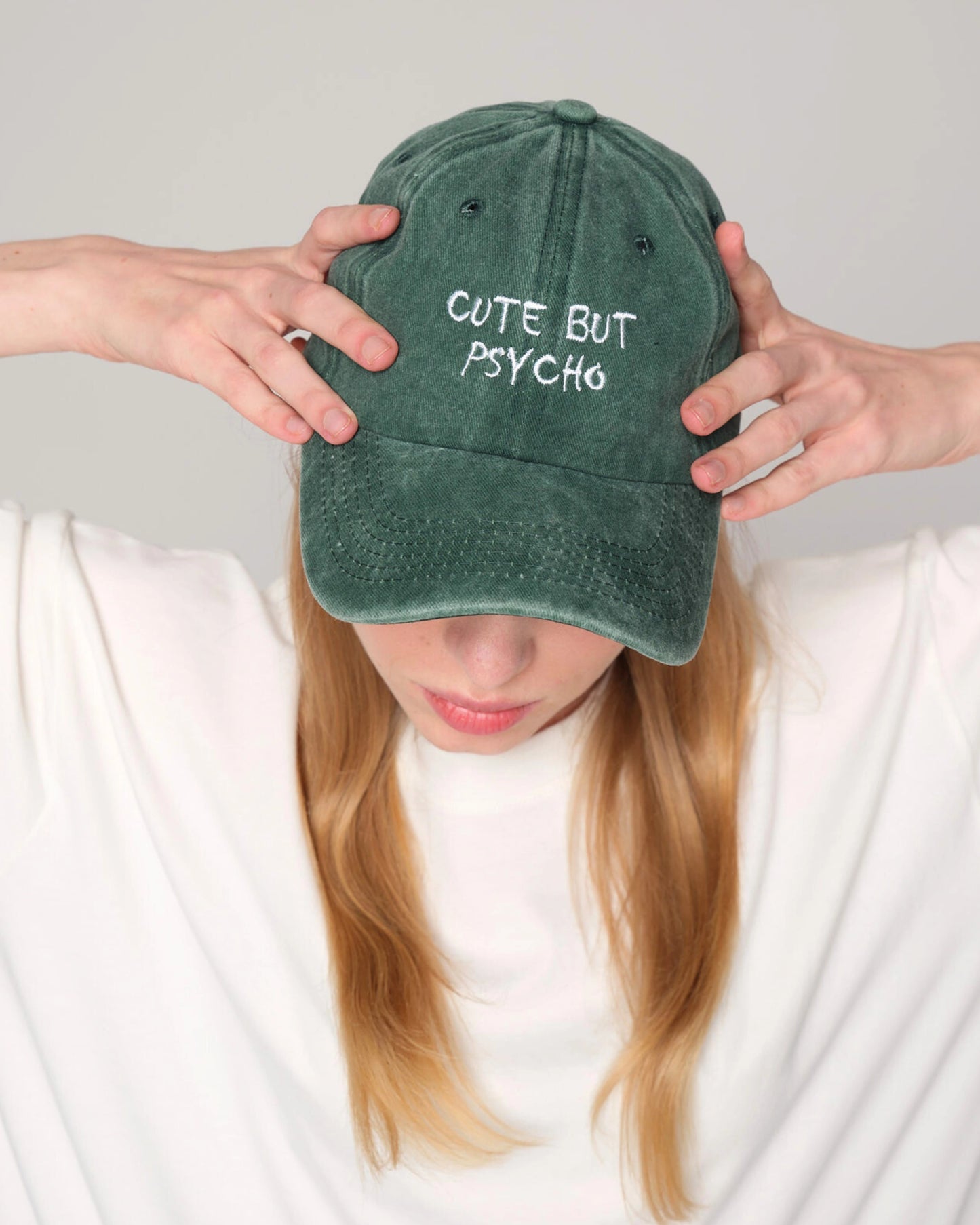 Front look of female model holding cute but psycho green washed cap