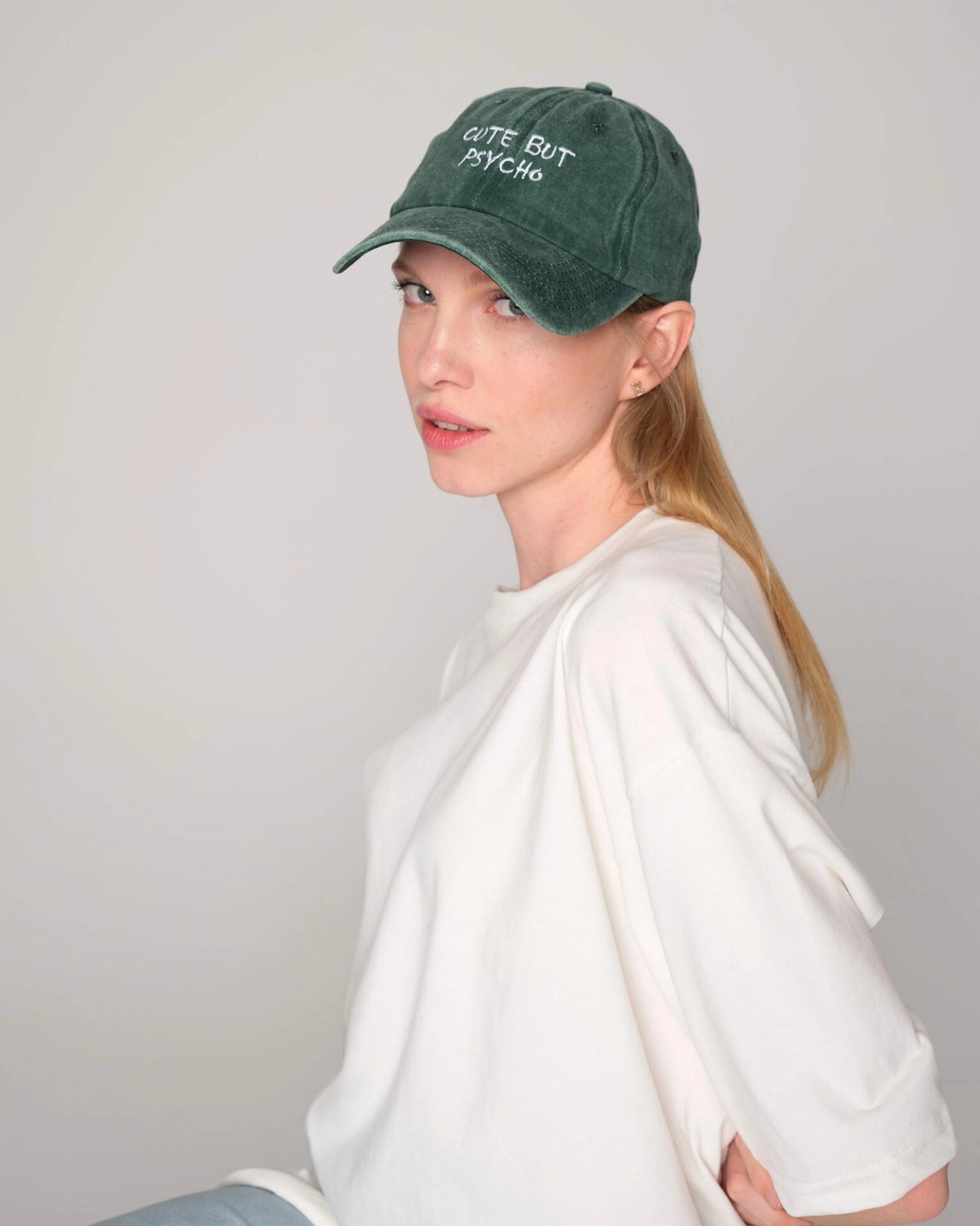 side look of female model wearing cute but psycho green washed cap