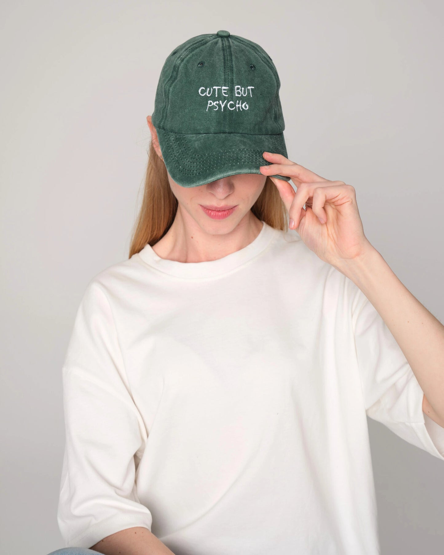 Front look of female model holding cute but psycho green washed cap