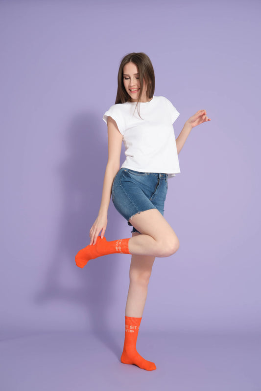 front view of a model wearing orange cute but psycho socks