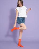 front view of a model wearing orange cute but psycho socks