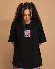 Person wearing a black t-shirt with a colorful graphic on a brown background
