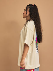 Woman wearing a cream t-shirt with colorful graphics on a brown background