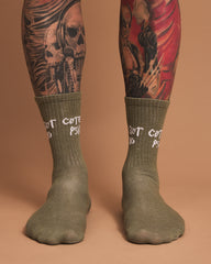 Green socks with text worn by a person with tattoos on a brown background