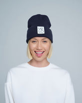 Person wearing a dusty navy beanie with a VELO logo on a gray background