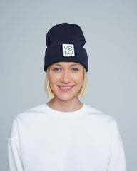 Person wearing a black beanie with a logo on a gray background