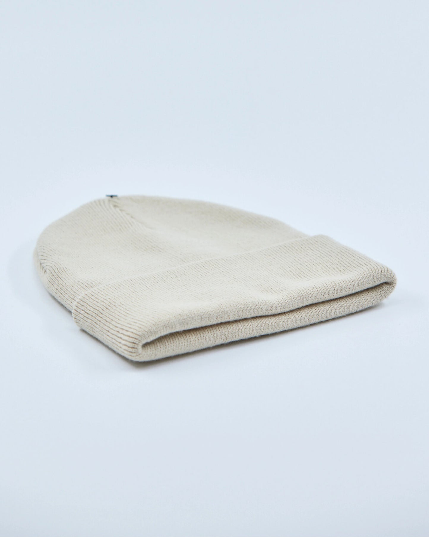Ecru white beanie hat on a light gray background