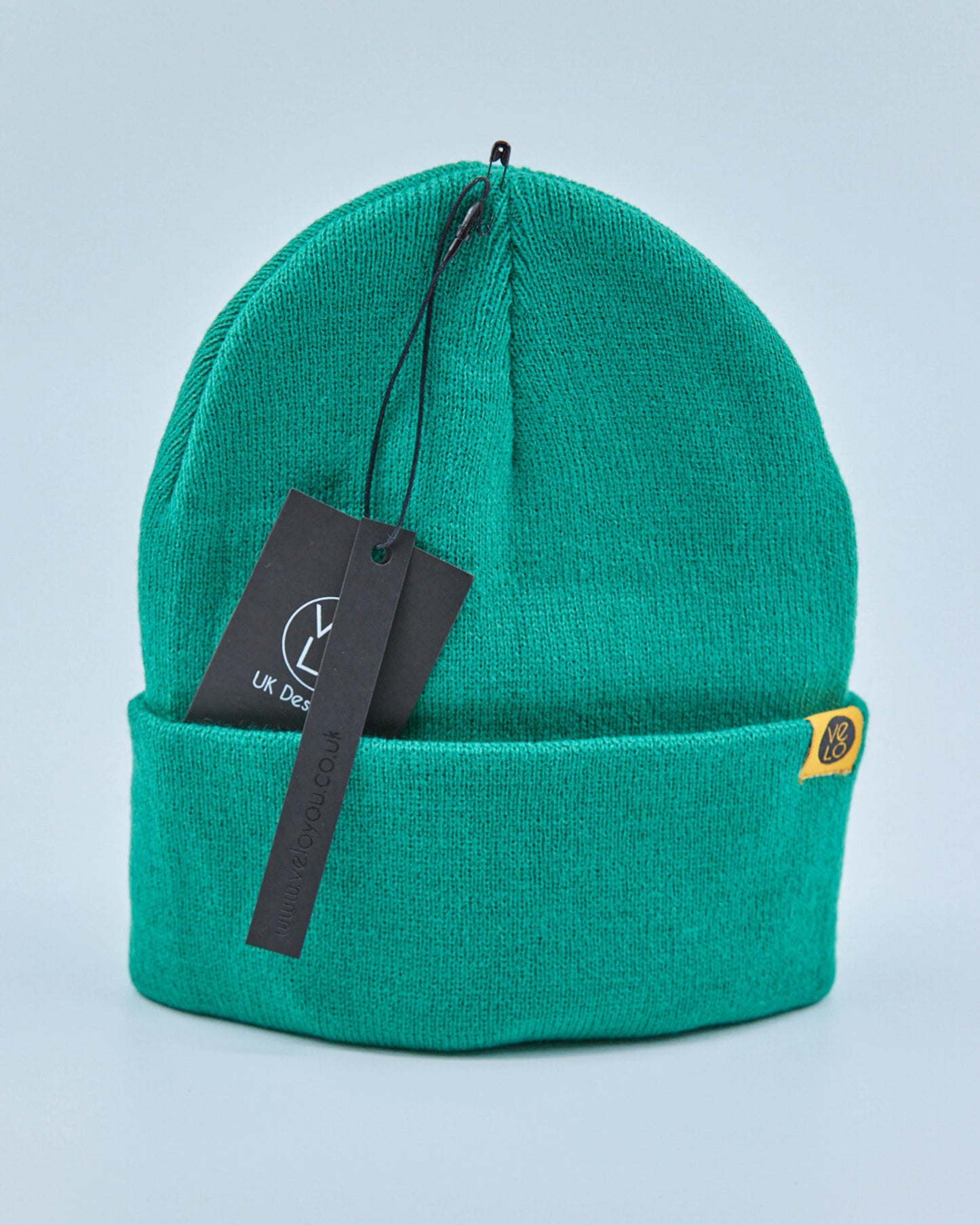 Green beanie with a tag on a light blue background