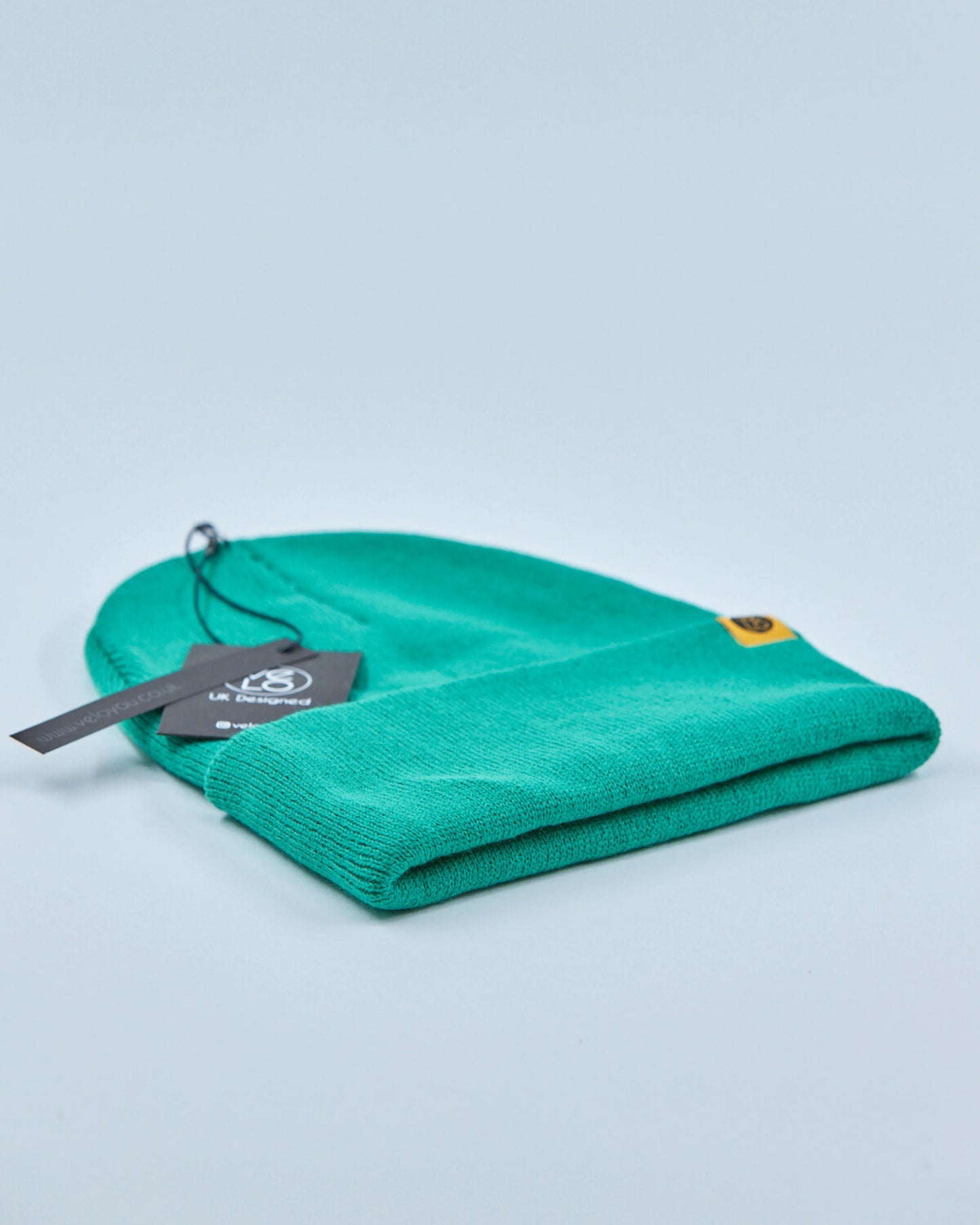 Green beanie with a tag on a light blue background