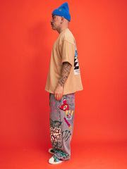 Person wearing a beige shirt, blue beanie, and colorful pants with text on an orange background