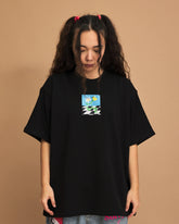 Person wearing a black t-shirt with a small graphic on a brown background