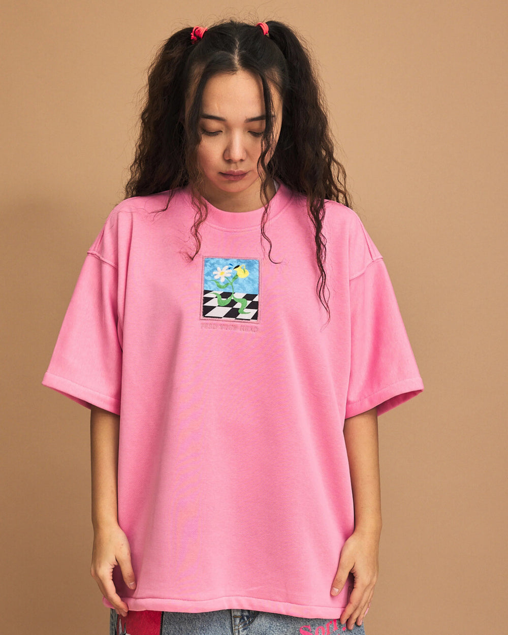 Person wearing a pink t-shirt with a graphic design on a brown background