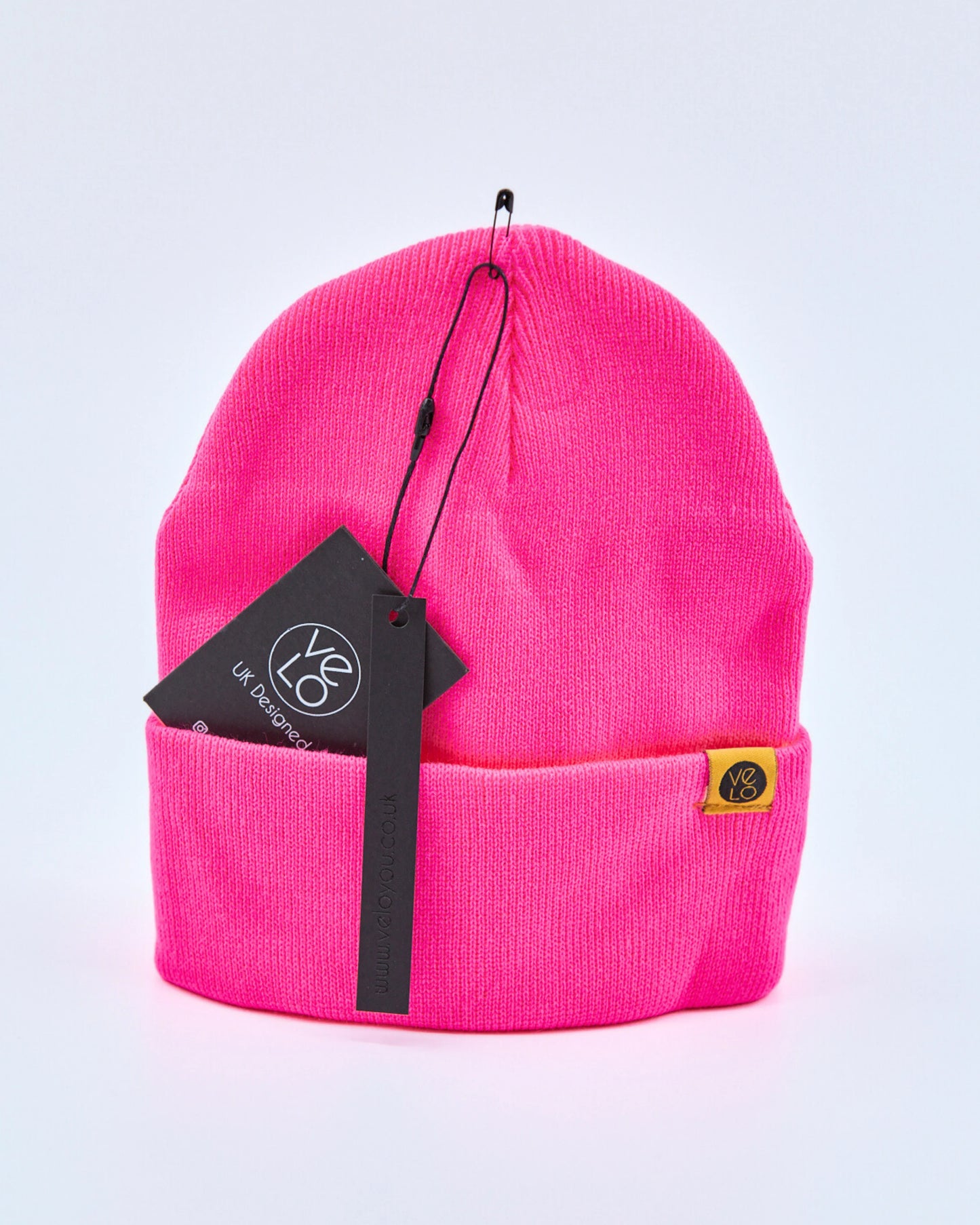 Fuschia pink beanie with a brand tag on a light gray background