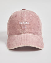 Pink corduroy cap with 'ahaha no.' text on a light gray background