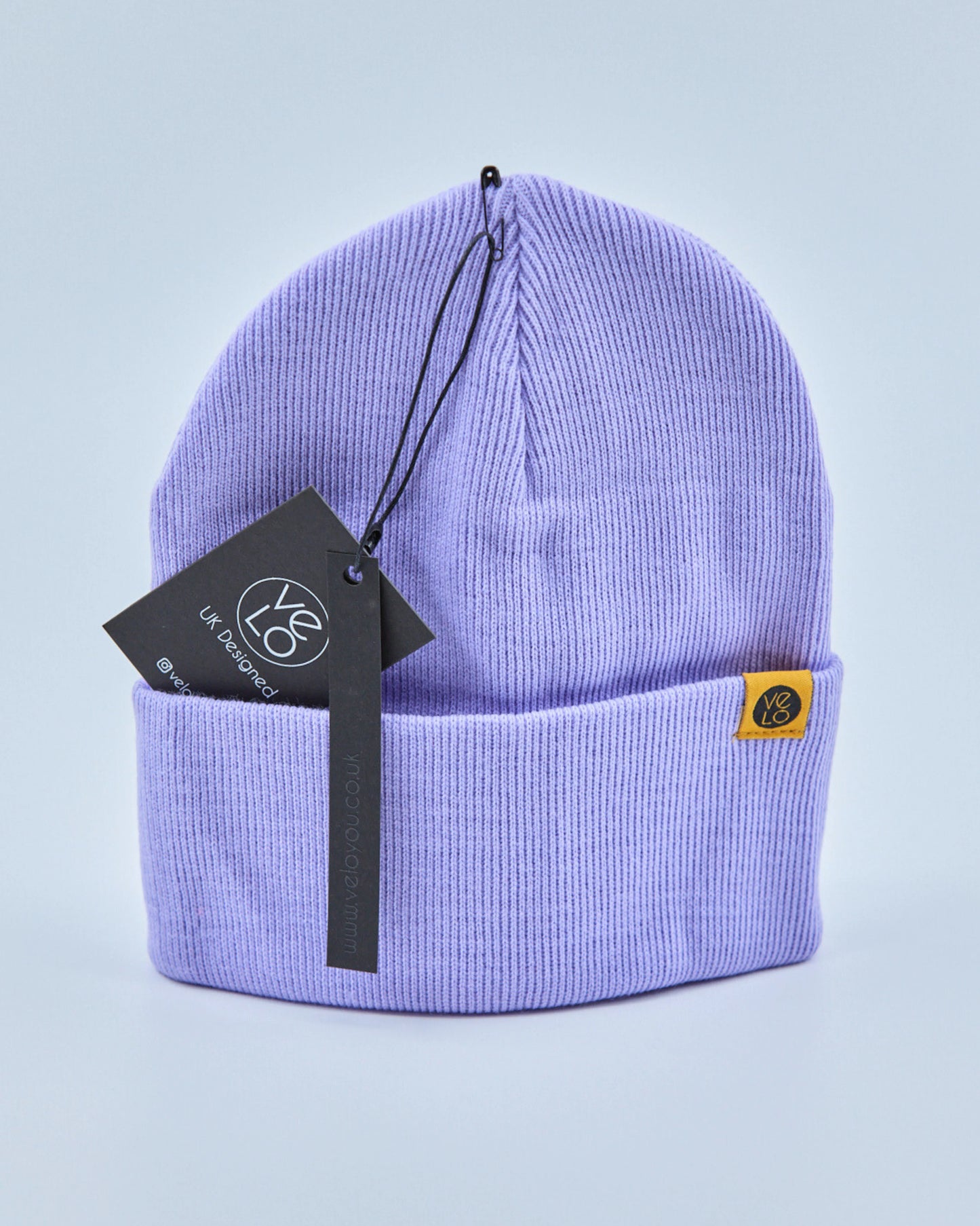 Lilac purple beanie with a brand tag on a light purple background