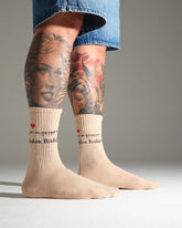 Beige socks with heart and London Bridge text and location designs worn by a person with tattoos on a neutral background