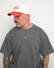 Man wearing a gray t-shirt with a small red logo and a white baseball cap with orange brim and orange 'love' text.