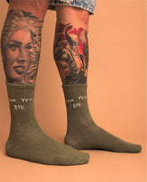 Person wearing green socks with text, standing against an orange background