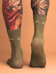 behind look of khaki green socks worn with tattoos on a beige background