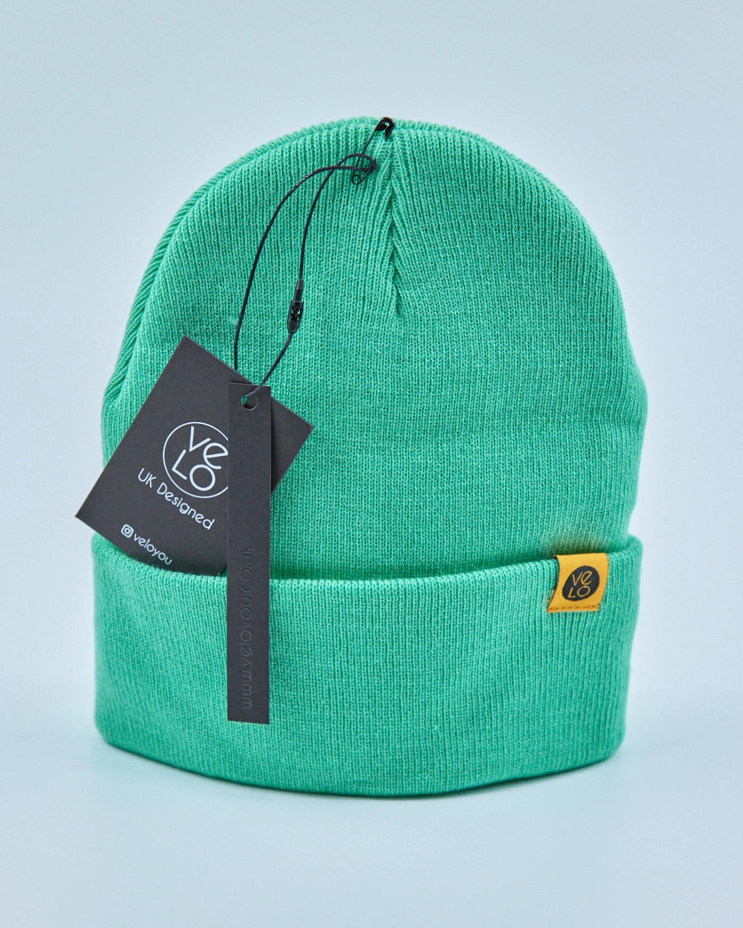 Mint green beanie with a tag on a light blue background