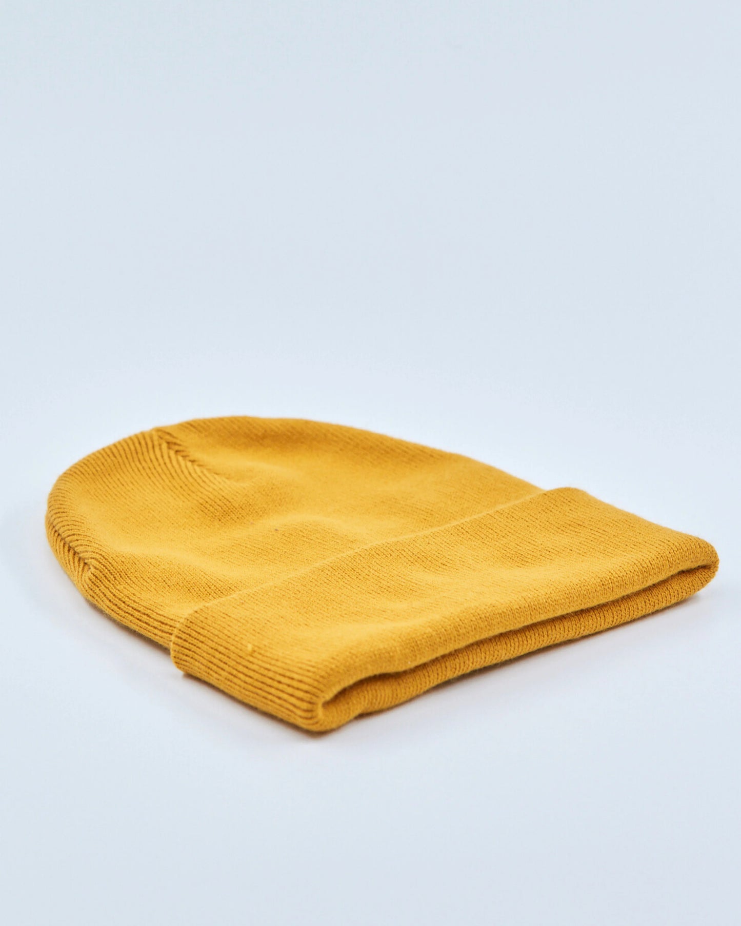 Mustard yellow beanie on a light gray background