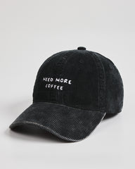 Black cap with 'NEED MORE COFFEE' text on a light gray background