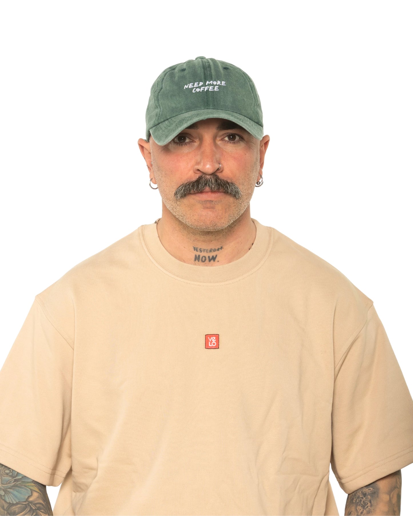 A man wearing the Need More Coffee Dark Green Washed Cap