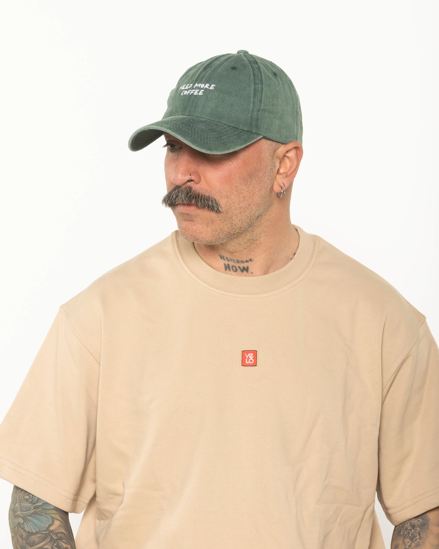 A man wearing the Need More Coffee Dark Green Washed Cap