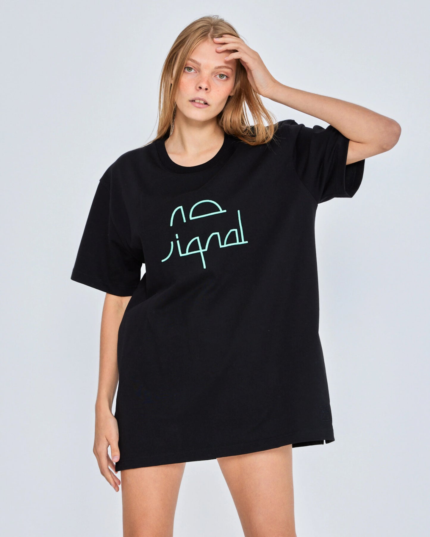 Woman wearing a black oversized t-shirt with a green logo on a white background