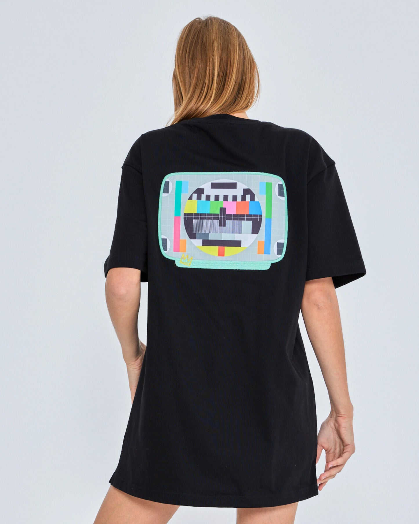 Person wearing a black t-shirt with a colorful graphic on the back against a white background