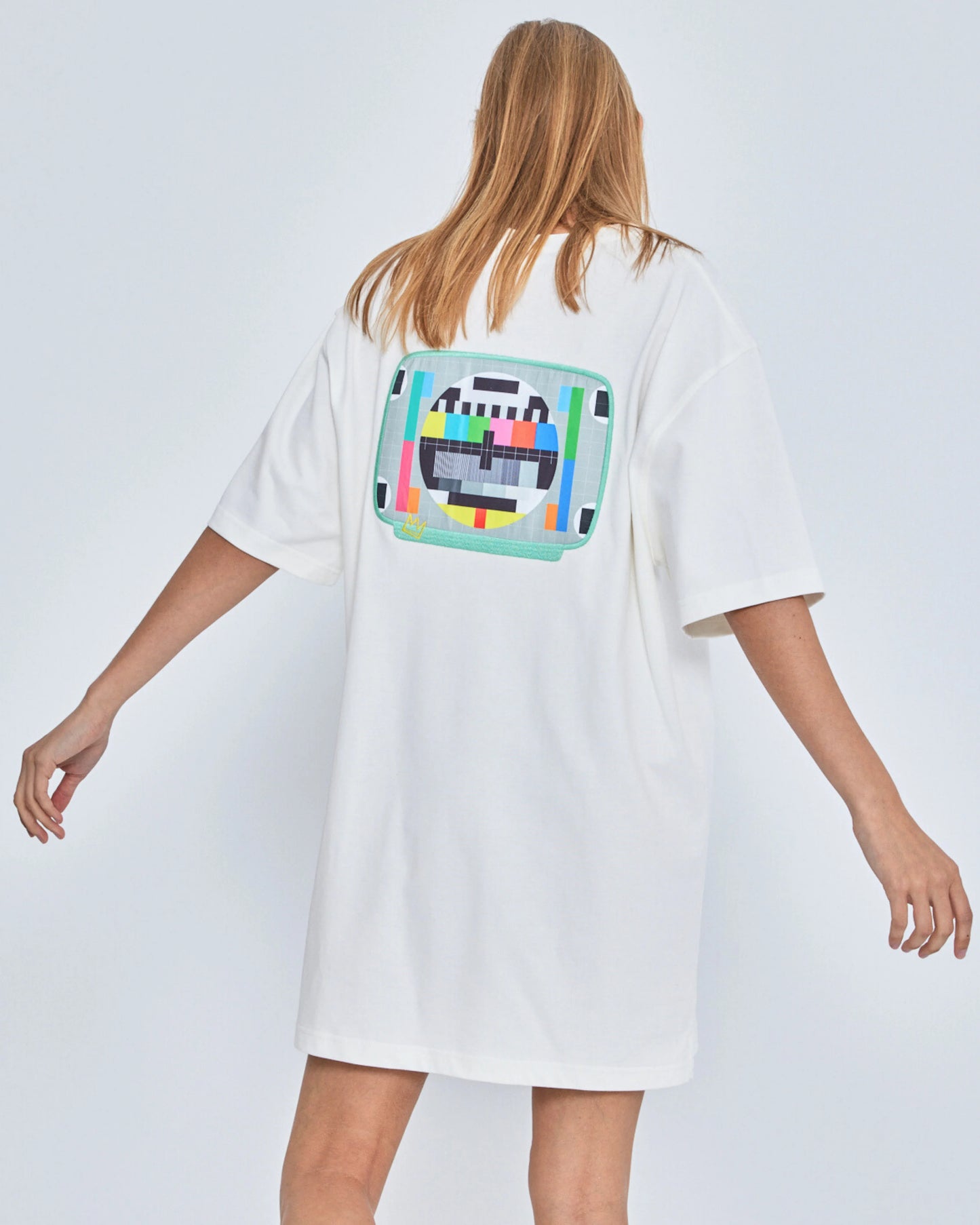 Person wearing a white t-shirt with a colorful graphic on the back against a plain background