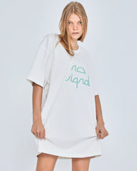 Woman wearing a white oversized t-shirt with green text on a light gray background