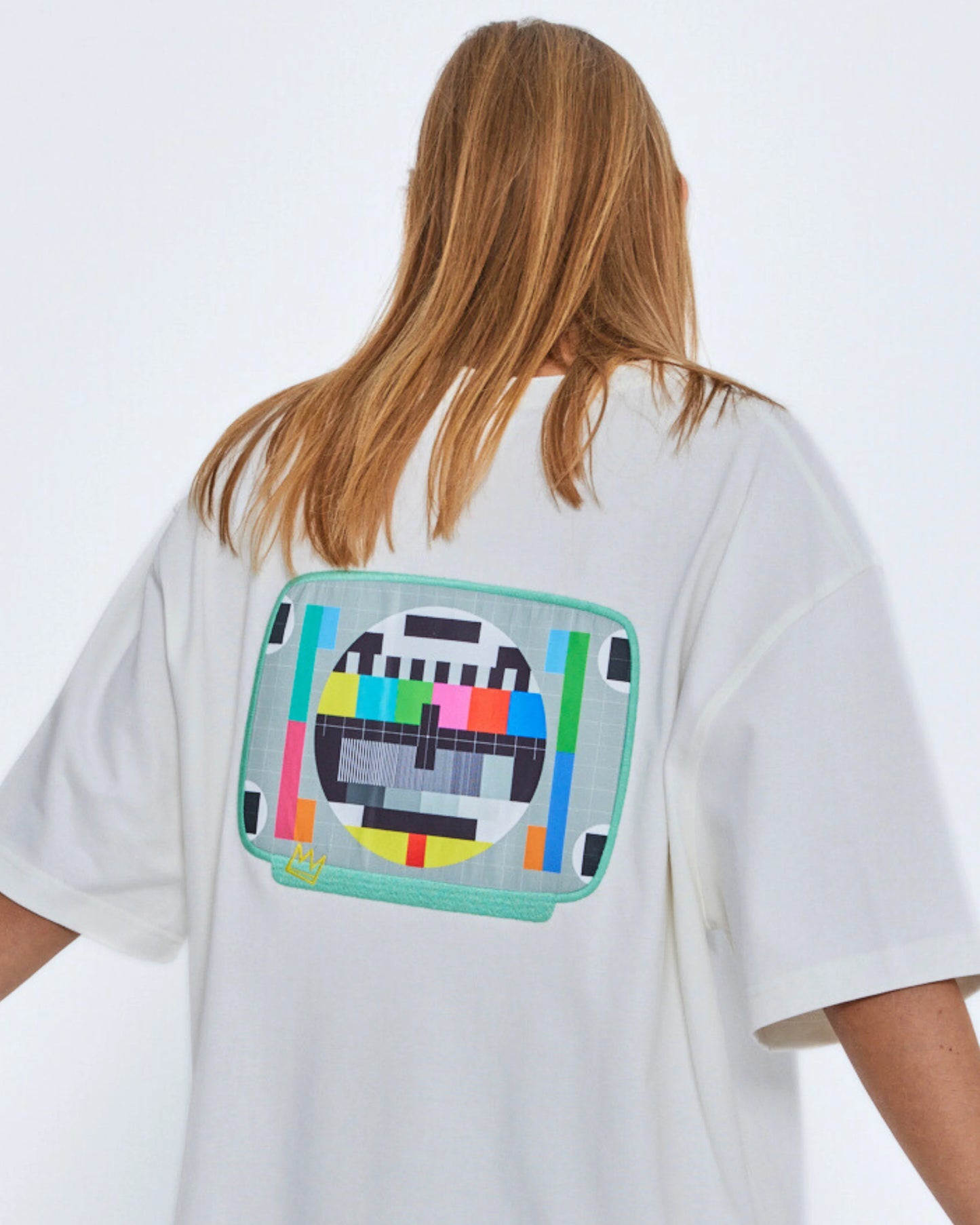 Person wearing a white t-shirt with a colorful graphic on the back against a plain background