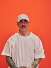 Man wearing a white cap and t-shirt against an orange background
