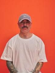 Man wearing a cap and white t-shirt against an orange background