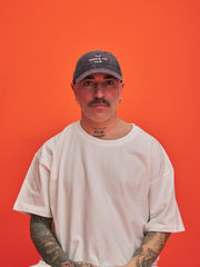 Man wearing a cap and white t-shirt against an orange background