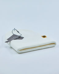 White beanie with a tag and logo on a light gray background