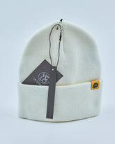 Off white beanie with a tag on a light gray background