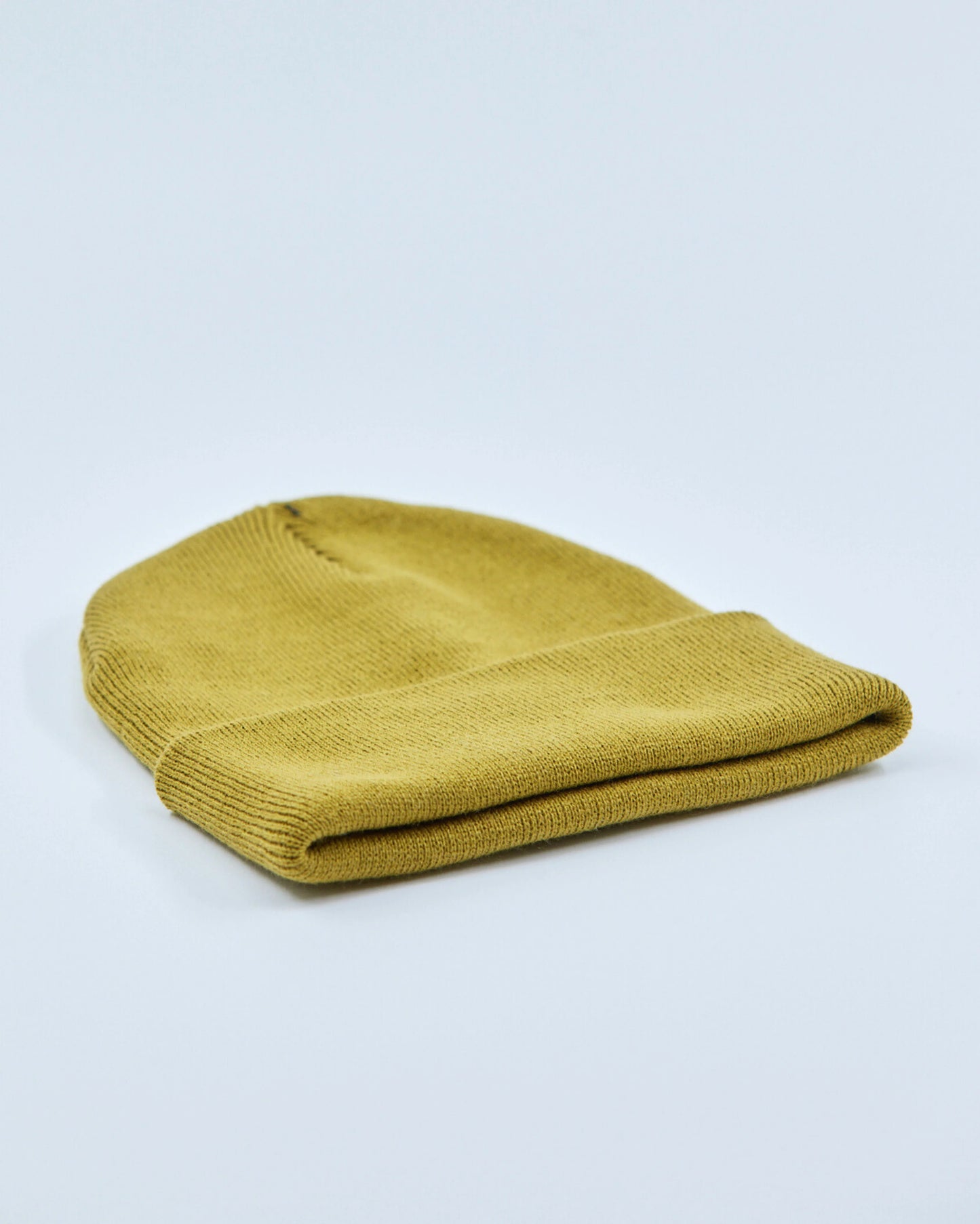 Mustard yellow beanie on a light gray background