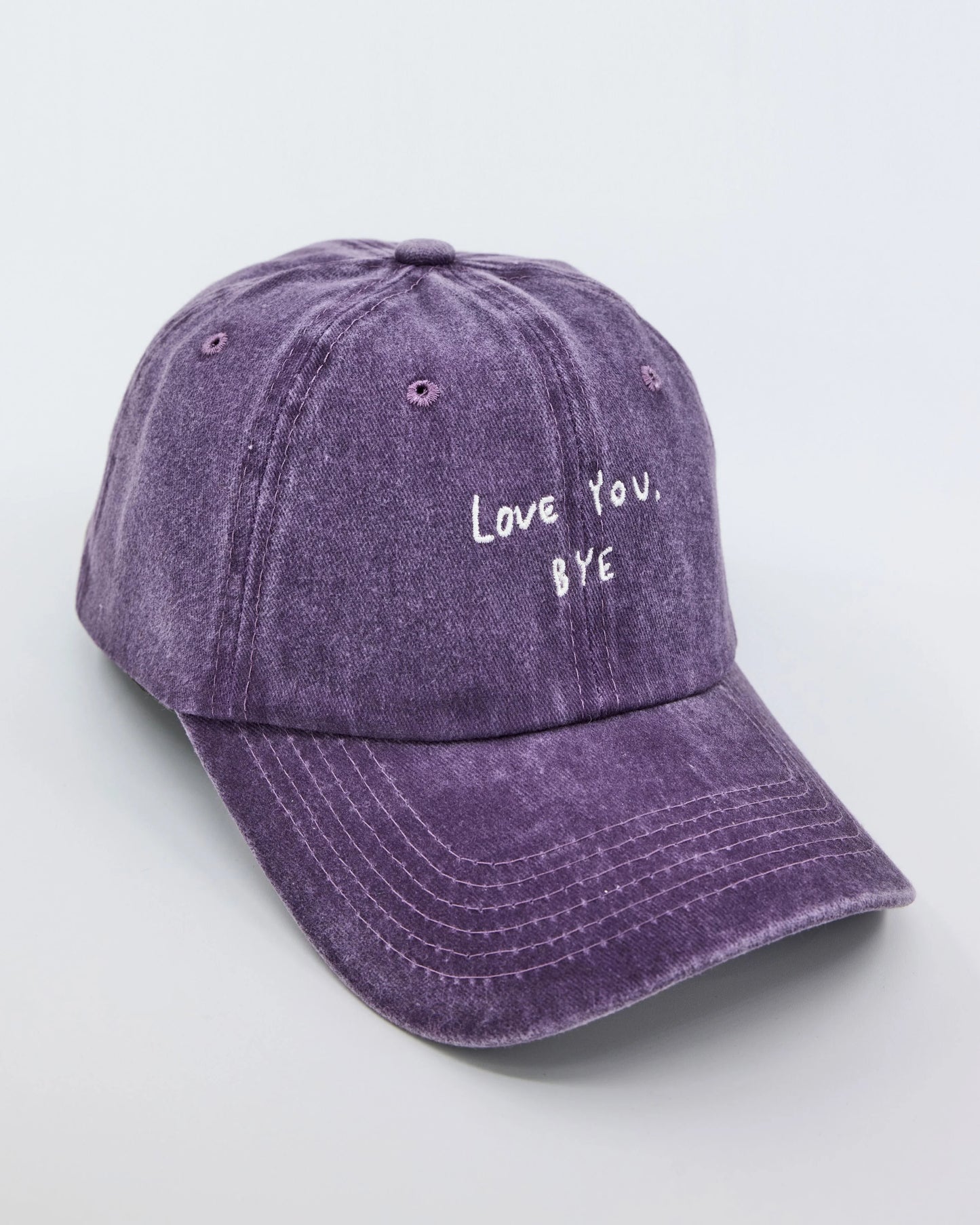 side view of purple washed cap with 'Love You, Bye' embroidered in white.